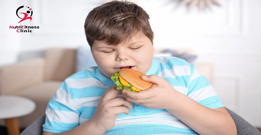 طفل يأكل برجر بشراهة وذلك من أسباب السمنة عند الأطفال